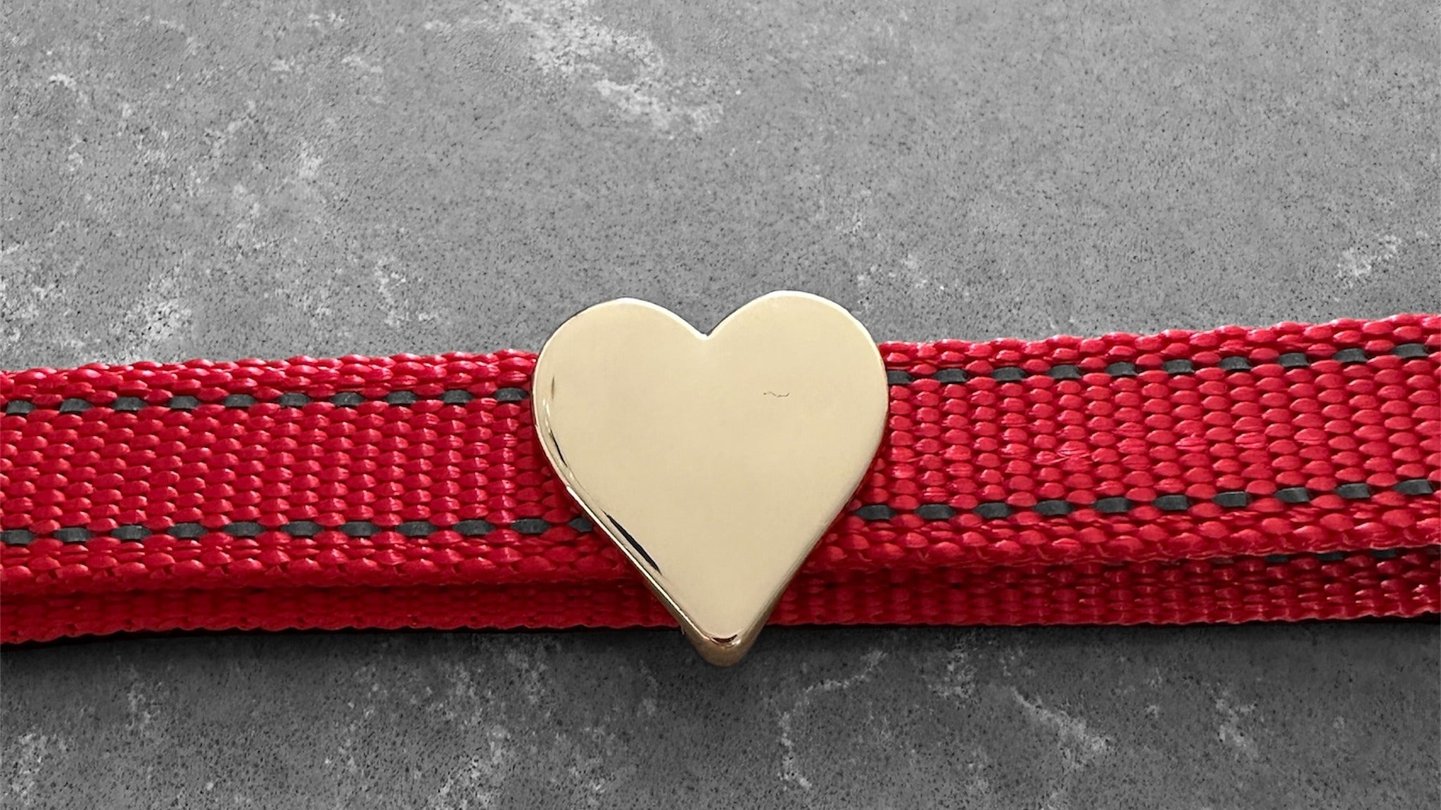 Red Pawz Please collar with a Gold heart charm on a concrete surface