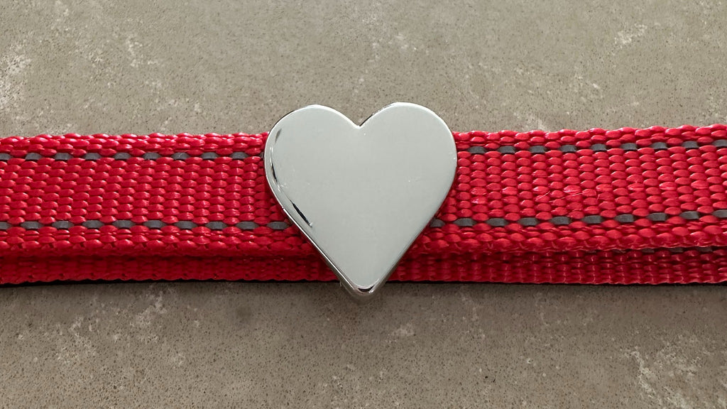 Red Pawz Please collar with a silver heart charm on a concrete surface